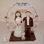 Couple de figurines en tenue de mariage, avec arche de pâtisserie