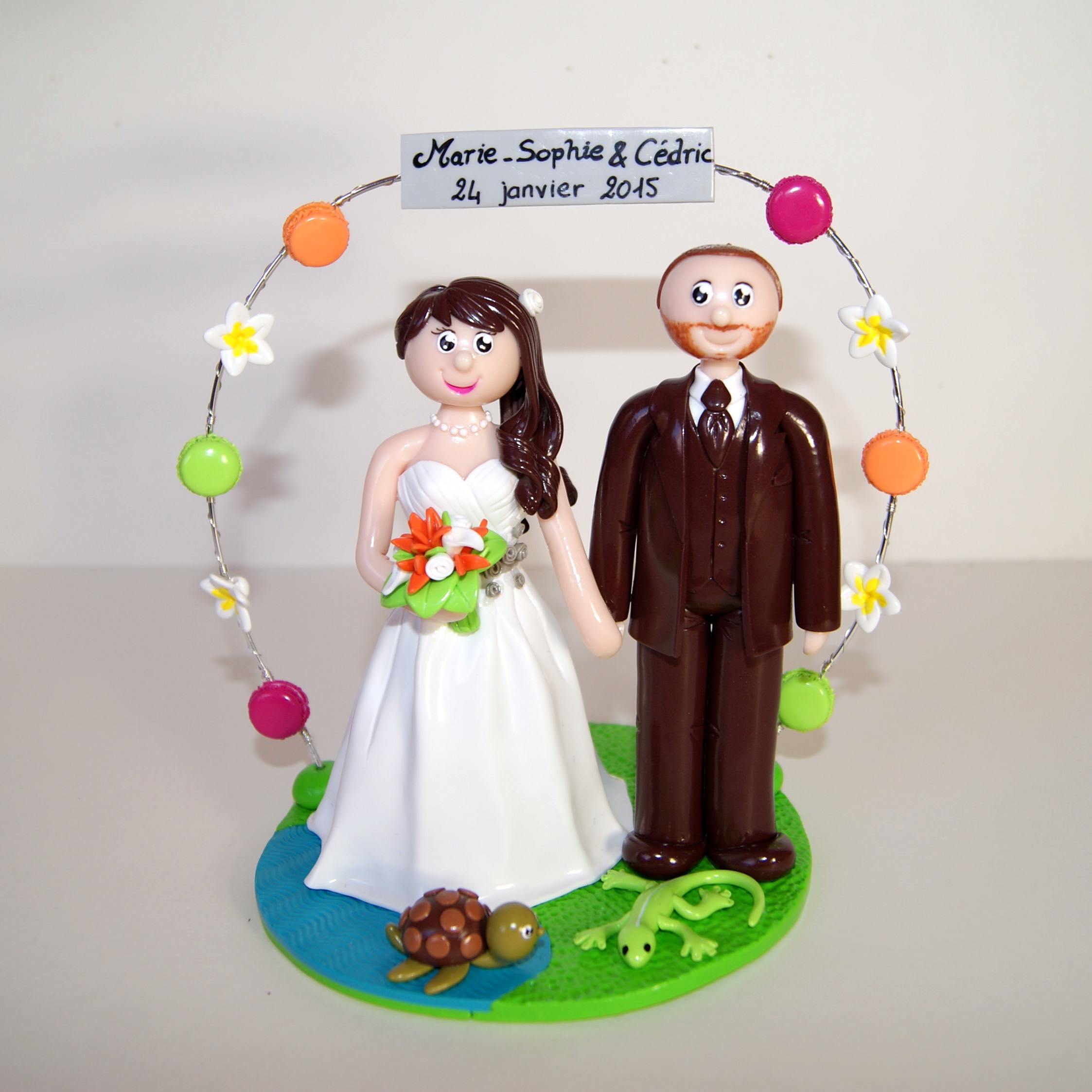 Figurines de couples de mariés, avec petite tortue et petit margouillat, arche de macarons et de fleurs de frangipanier