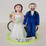 Figurines en tenue de mariage, vélo en arrière-plan avec panier rempli de fleurs champêtres