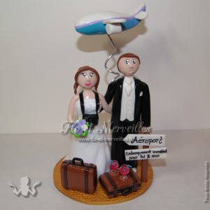 couple de figurine, en tenue de mariage, avec un avion et des valises