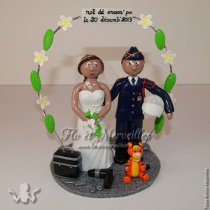 couple de figurines avec mariée en robe de mariage, marié en tenue de gendarme, une peluche Tigrou et une arche de frangipanier